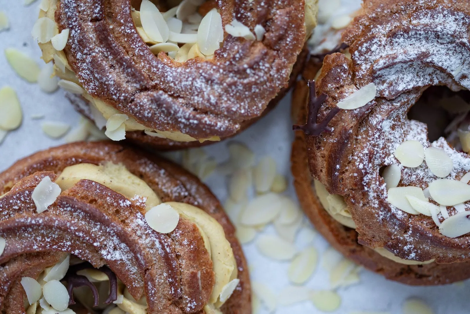 Paris-Brest individuels parsemés d’amandes effilées, la crème pralinée visible
