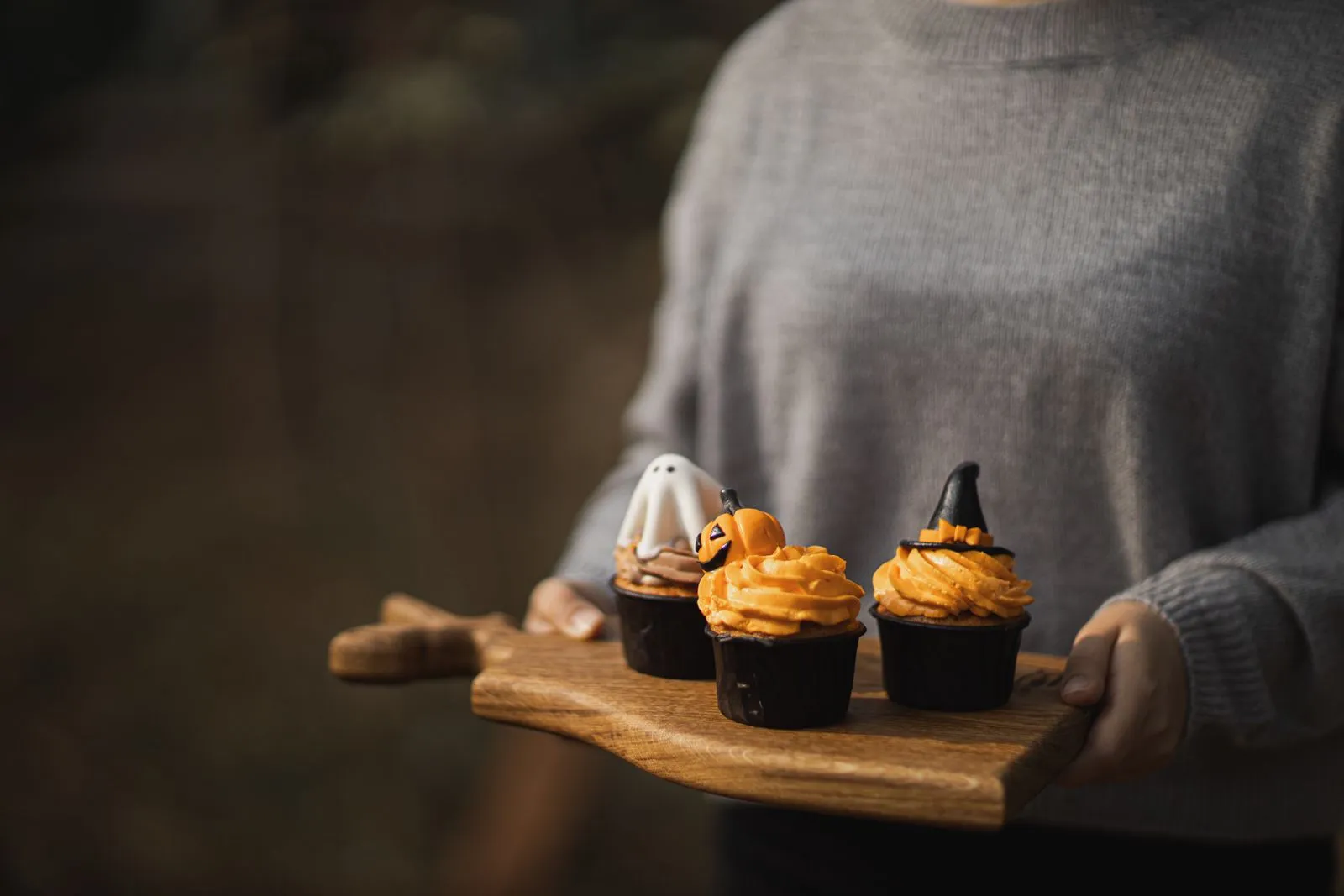 Cupcakes d’Halloween décorés en citrouilles et en toile d’araignée sur une planche